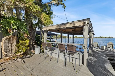 a patio with wooden floor a yard a table and chairs