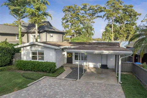 a view of a white house next to a yard with plants and trees