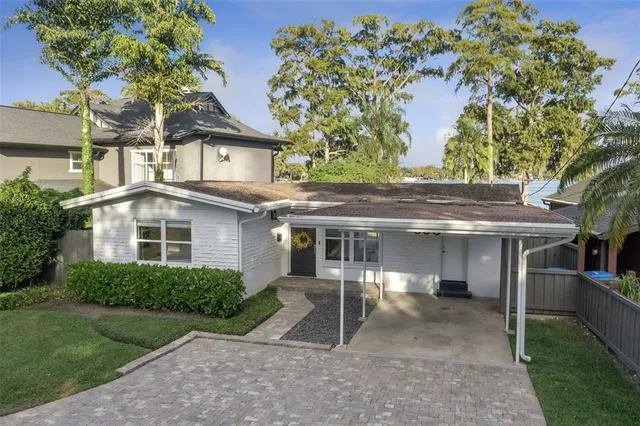 a view of a white house next to a yard with plants and trees