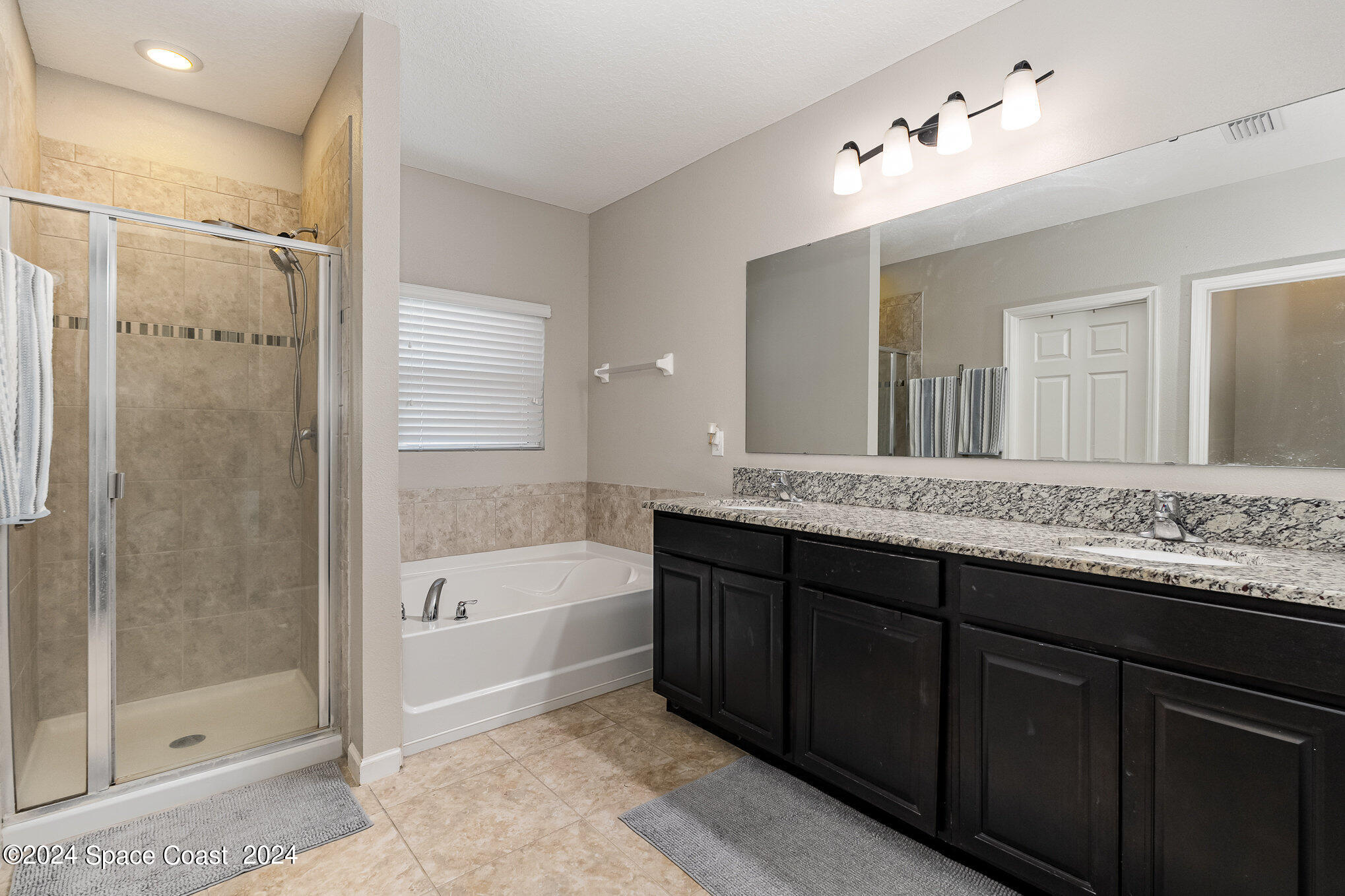 4210 Harvest Circle Rockledge, FL 32955 - Photo 15 of 24 a bathroom with a granite countertop sink a mirror a bathtub and shower