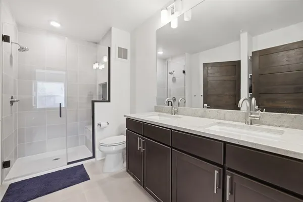 a bathroom with a double vanity sink toilet and shower