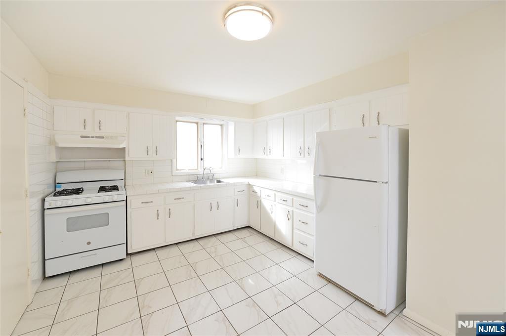 100 Eastern Way Rutherford, NJ 07070 - Photo 7 of 19 a kitchen with cabinets and white appliances