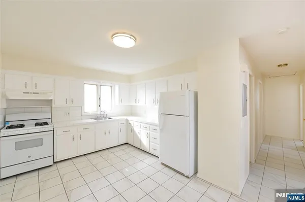 a kitchen with white cabinets and white appliances