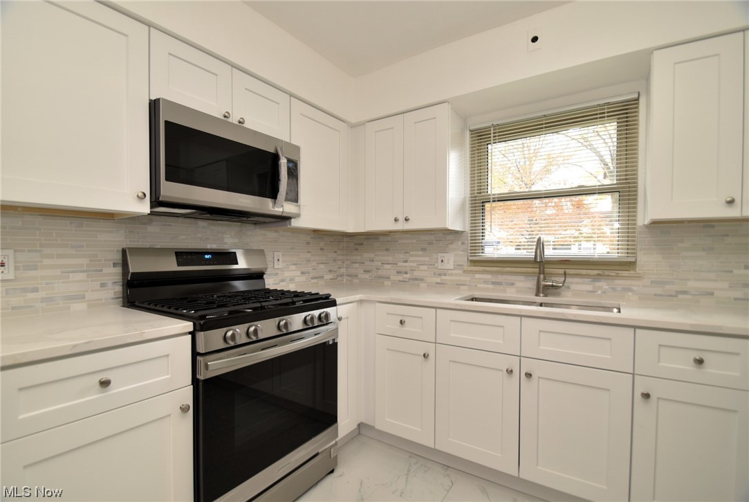 3681 Brinkmore Road Cleveland Heights, OH 44121 - Photo 12 of 27 Kitchen with light tile floors, sink, stainless steel appliances, tasteful backsplash, and white cabinetry