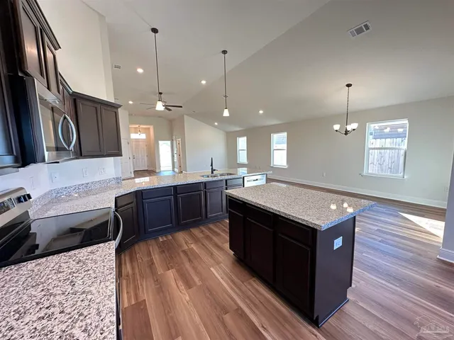 a large kitchen with stainless steel appliances granite countertop a sink a stove and a wooden floors