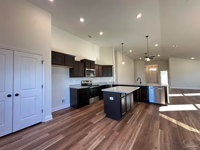 a large kitchen with a center island wooden floor and stainless steel appliances