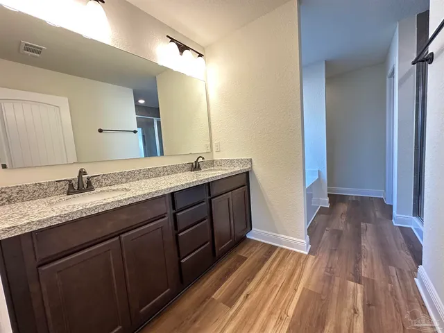 a spacious bathroom with a granite countertop sink toilet a large mirror a vanity and shower