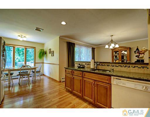 15 Warwick Road Edison, NJ 08820 - Photo 8 of 25 a kitchen with stainless steel appliances granite countertop a stove a sink dishwasher and a dining table with wooden floor
