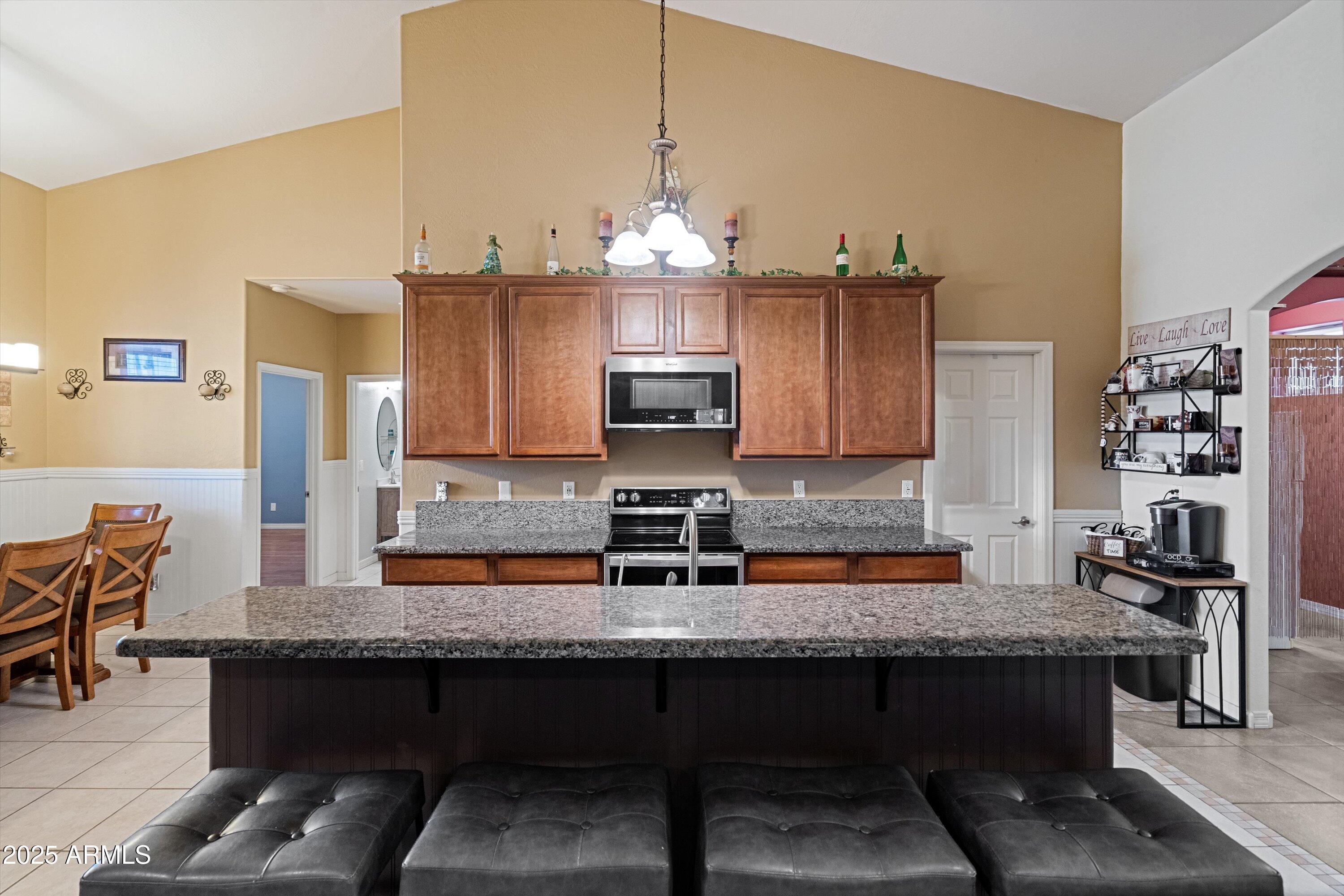 35947 West Buckeye Road Tonopah, AZ 85354 - Photo 15 of 54 a kitchen with stainless steel appliances granite countertop a sink dishwasher a microwave oven and a dining table with wooden floor