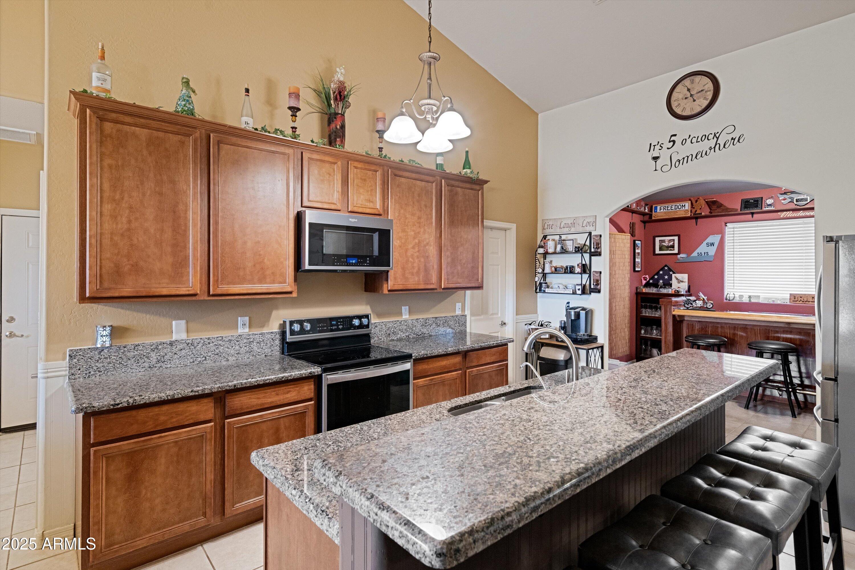 35947 West Buckeye Road Tonopah, AZ 85354 - Photo 19 of 54 a kitchen with stainless steel appliances granite countertop a stove a sink dishwasher and microwave with wooden floor