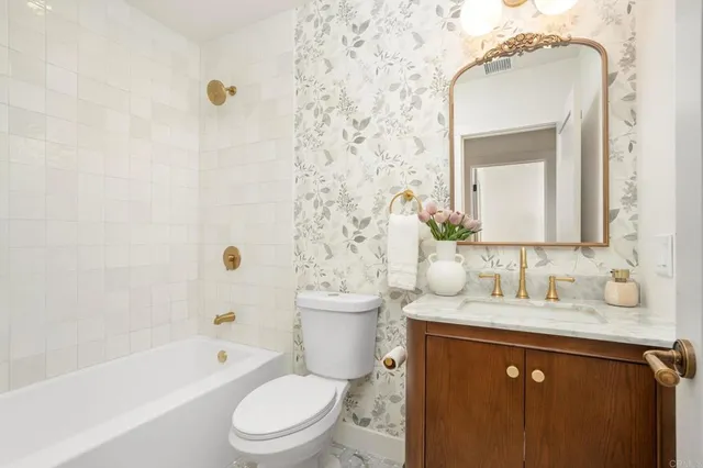 a bathroom with a granite countertop sink toilet a mirror and bathtub