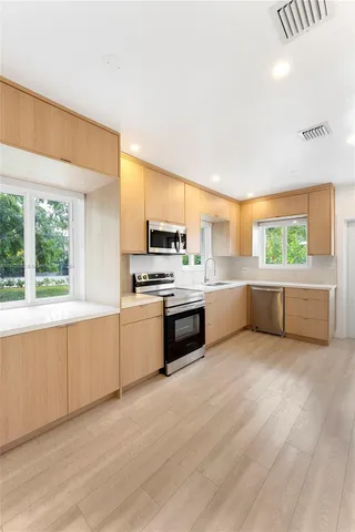 a large kitchen with a large window and stainless steel appliances