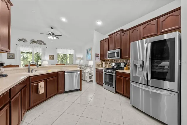 a white kitchen with stainless steel appliances and chandelier