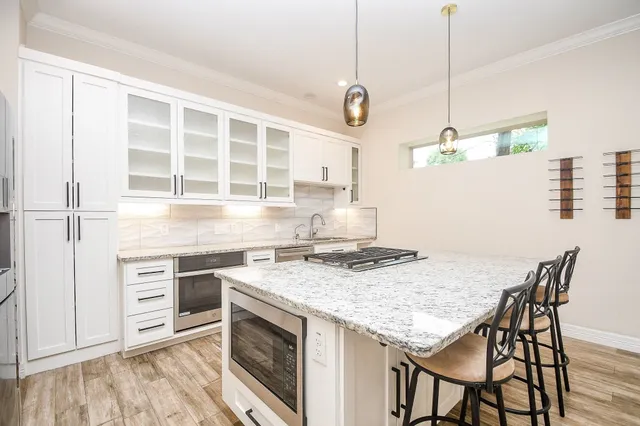 a kitchen with a stove a refrigerator and a wooden floor