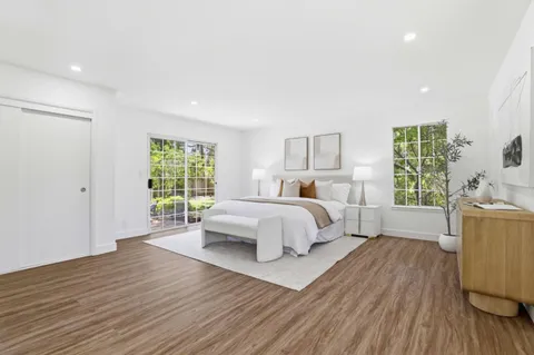 a spacious bedroom with a bed and wooden floor