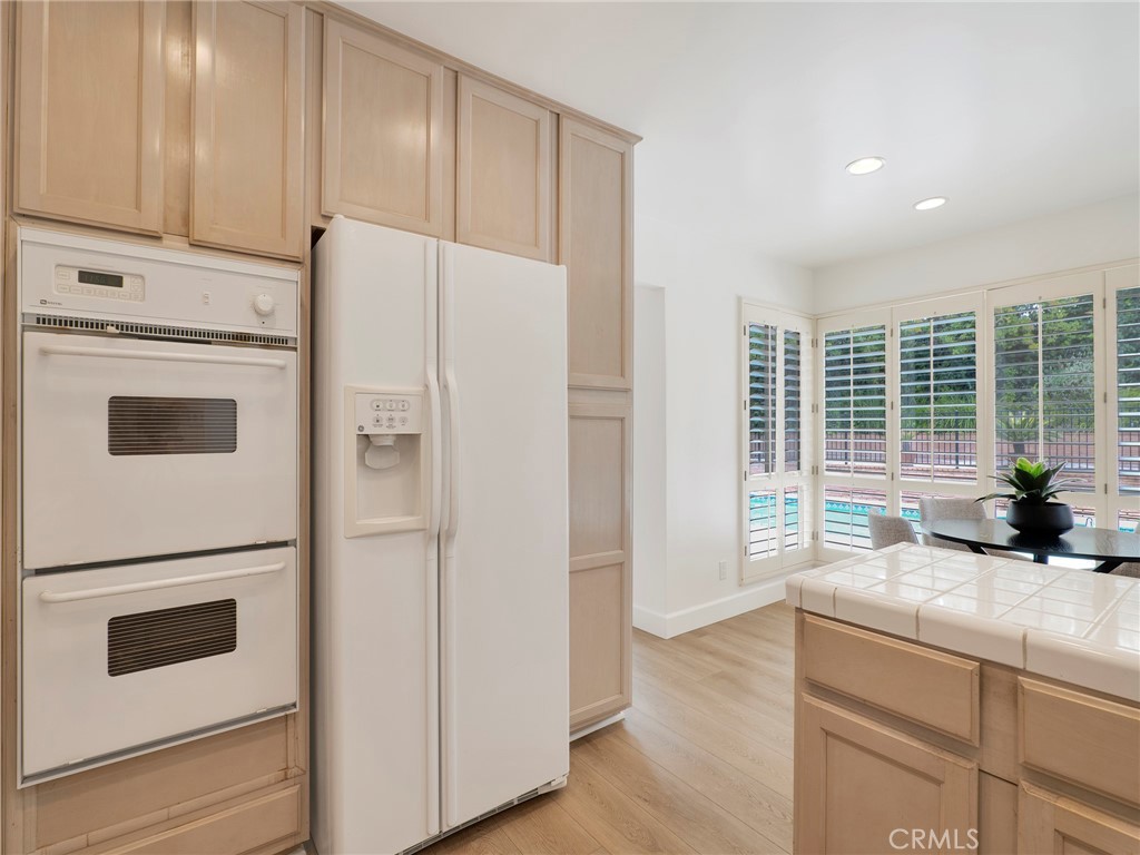 22649 Town Crier Road Calabasas, CA 91302 - Photo 28 of 47 a kitchen with refrigerator cabinets and wooden floor
