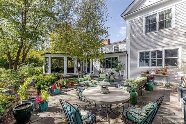 a view of a patio with table and chairs potted plants and large tree
