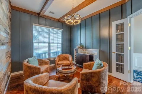 a living room with furniture a chandelier and wooden floor