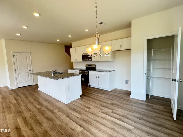 a large kitchen with stainless steel appliances kitchen island a large counter top and a wooden floors