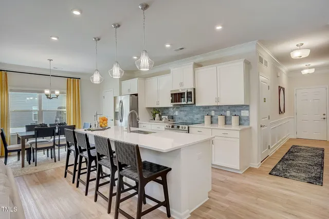 a kitchen with stainless steel appliances a dining table chairs and sink