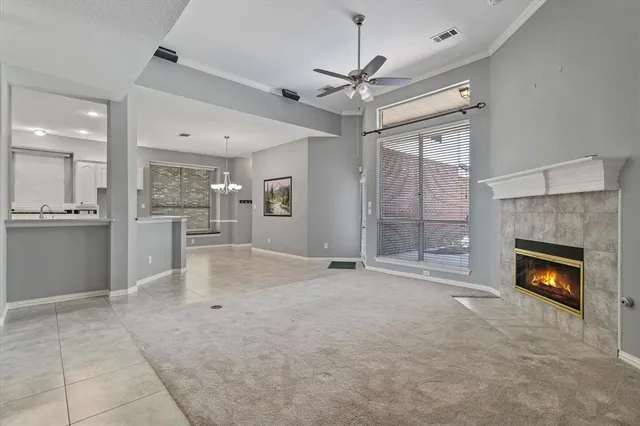 a view of a livingroom with a fireplace a ceiling fan and windows