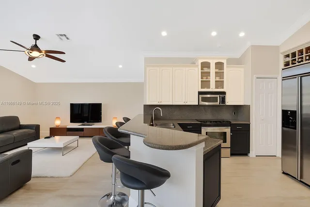 a kitchen with a stove a refrigerator and a living room view
