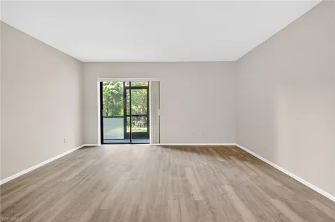 an empty room with chandelier fan and windows