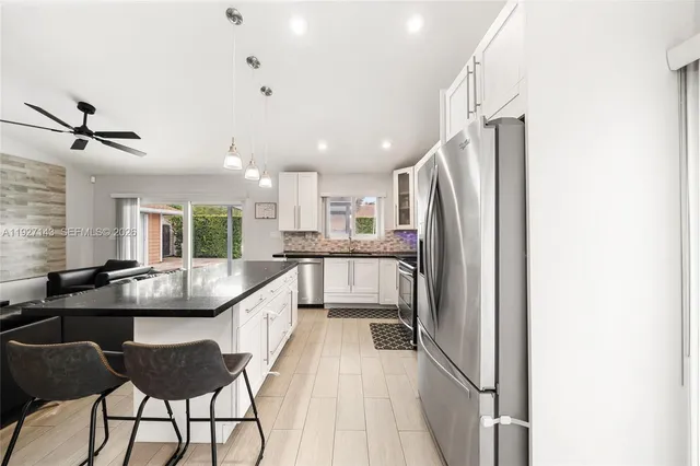 a kitchen with stainless steel appliances granite countertop a kitchen island hardwood floor sink stove and refrigerator