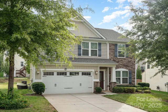a view of a white house next to a yard with big trees