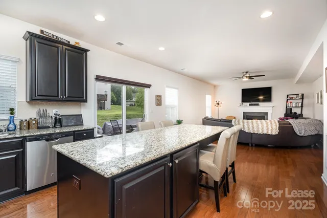 a kitchen with granite countertop a stove a sink a dining table and chairs