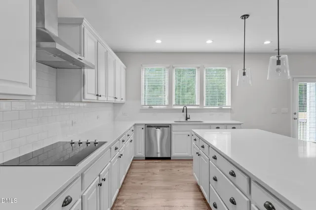 a view of a kitchen with stainless steel appliances granite countertop a stove a sink a center island and cabinets