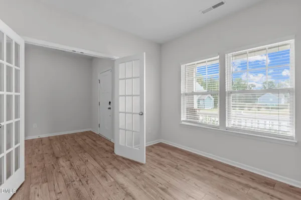 a view of an empty room with wooden floor and a window