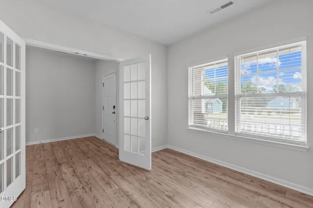 a view of an empty room with wooden floor and a window