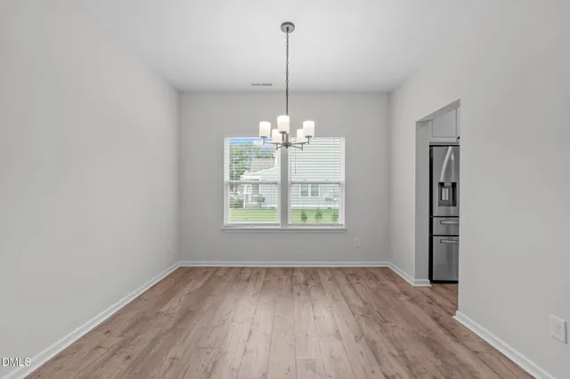 a view of a room with wooden floor chandelier and window
