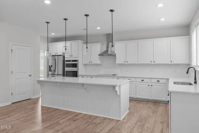 a kitchen with stainless steel appliances granite countertop a sink a stove a refrigerator and island with wooden floor