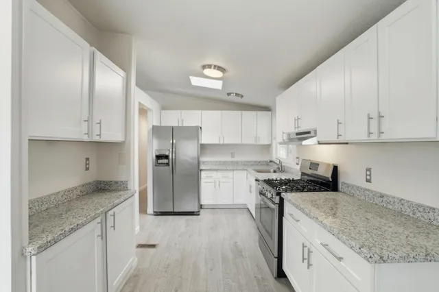 a kitchen with stainless steel appliances granite countertop a sink stove and refrigerator
