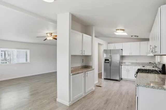 a kitchen with granite countertop a refrigerator and a stove top oven
