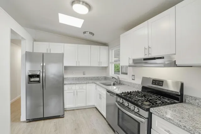 a kitchen with stainless steel appliances granite countertop a stove a refrigerator and a sink