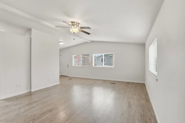 a view of an empty room with a window and wooden floor