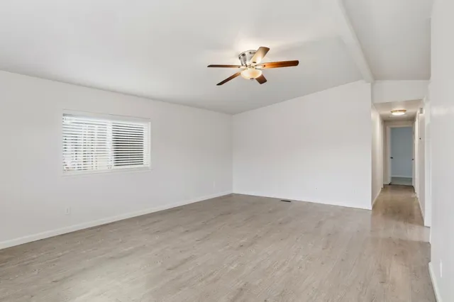 a view of an empty room with chandelier fan and a window