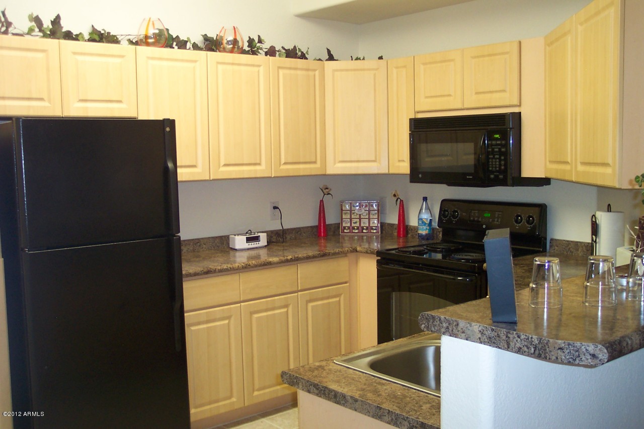 5303 North 7th Street, Unit 113 Phoenix, AZ 85014 - Photo 7 of 21 a kitchen with granite countertop a refrigerator a stove a sink a window and cabinets