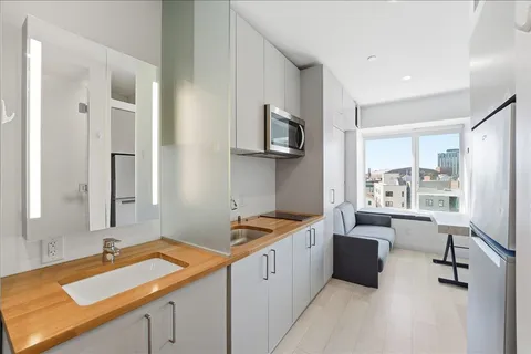 a view of a kitchen with a sink and dishwasher with wooden floor