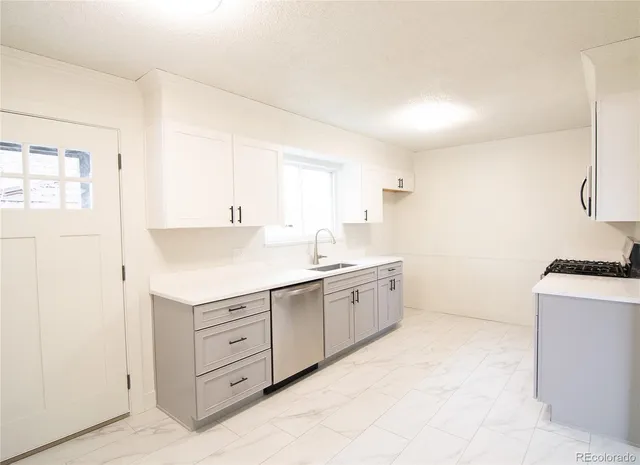 a kitchen with granite countertop a sink a stove a refrigerator and white cabinets