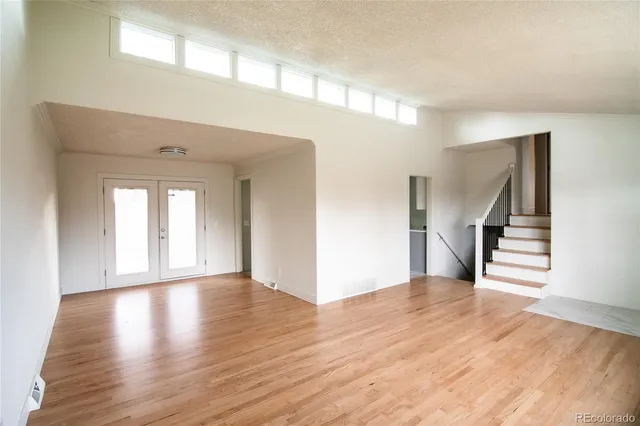 a view of an empty room with wooden floor and stairs