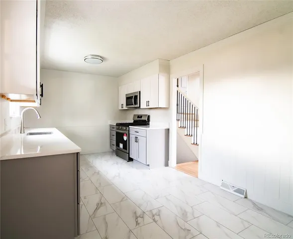a kitchen with granite countertop a sink stove and refrigerator