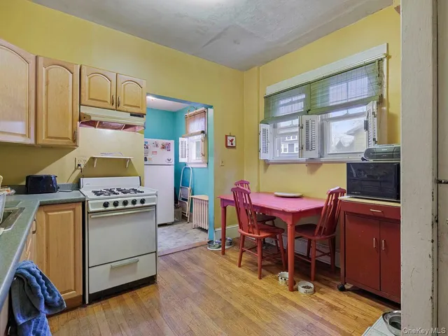 a kitchen with stainless steel appliances granite countertop a stove a refrigerator a dining table and chairs with wooden floor