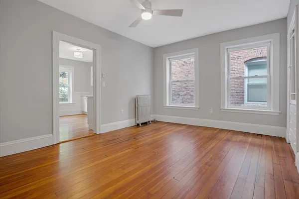an empty room with wooden floor and windows