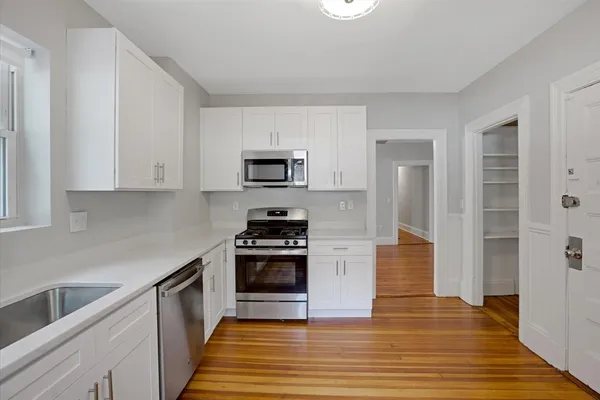 a kitchen with granite countertop a stove a sink and a refrigerator