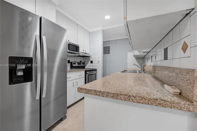 a kitchen with stainless steel appliances granite countertop a refrigerator a stove and a sink