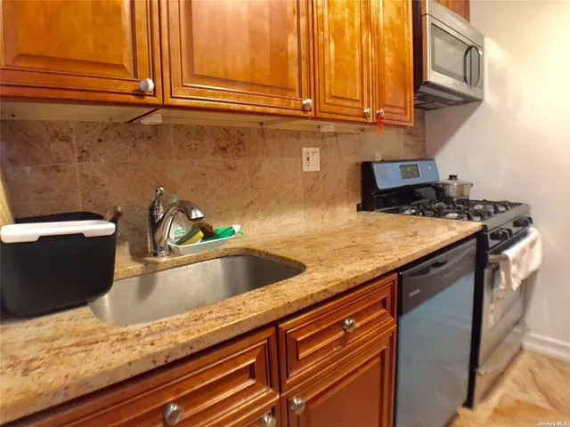 a view kitchen with granite countertop stainless steel appliances sink microwave and stove